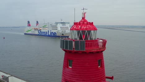 Slow-drone-orbit-around-red-flickering-light-of-Poolbeg-lighthouse-with-cruise-ship-entering-Dublin-harbor