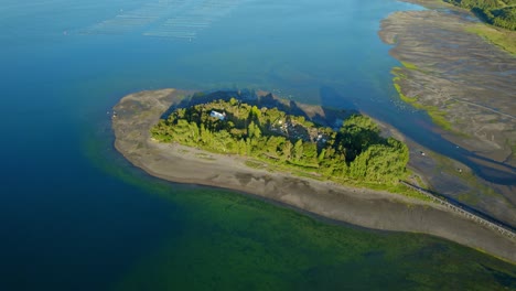 Luftbild-Drohnenlandschaft,-Grüne-Aucar-Insel-Rund-Um-Die-Türkisfarbene-Bucht,-Chiloé-Friedhof