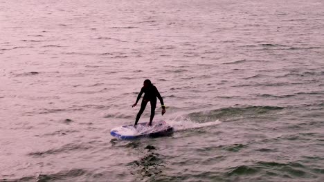 aerial-tracking-of-sportsman-falls-while-practicing-hydrofoil-on-the-Tagus-River,-with-Caparica-in-the-background