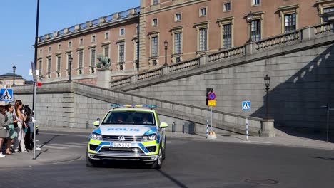 Swedish-police-cars-in-front-of-Royal-Palace-with-spectators,-sunny-day