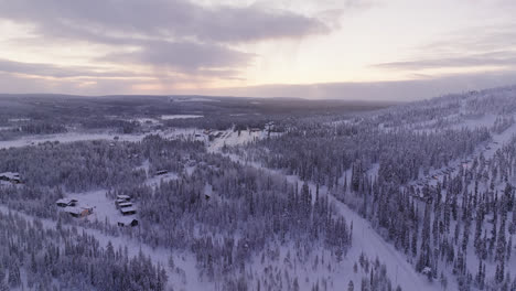 Drone-shot-approaching-a-parking-lot-under-the-slopes-of-Iso-Syote,-winter-in-Finland