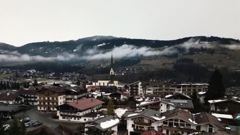 Church-tower-of-Kirchberg-township-with-Alps-mountains-in-background,-aerial-view