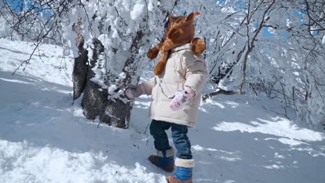 Toddler-Girl-Playing-With-Snow-Capped-on-Tree-Branches-in-Snow-Covered-Balwangsan-Mountain-Mona-Park---slow-motion,-Gangwon-do,-South-Korea