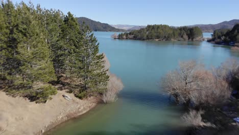 Fast-drone-view-over-Mountain-artificial-lake-panning-up-winter-sunny-day