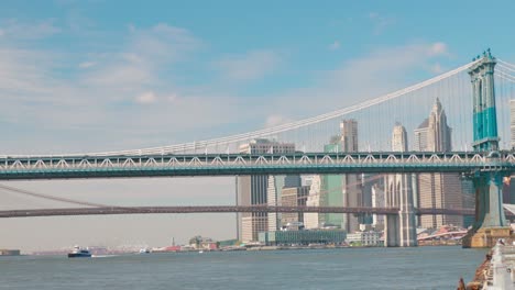 Berühmte-Amerikanische-Brooklyn-Bridge-über-Den-East-River-Mit-Blaugrüner-Skyline-Von-New-York-City