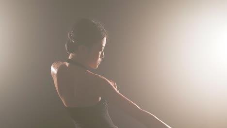 Japanese-ballerina-performing-ballet-slowly-on-a-stage-of-illuminated-smoke