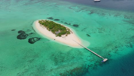 Drohne-Fliegt-über-Einer-Privaten-Insel-In-Fidschi-Mit-Einem-Kreuzfahrtschiff-Im-Hintergrund,-Während-Ein-Kleines-Schlauchboot-Am-Strand-Ankommt