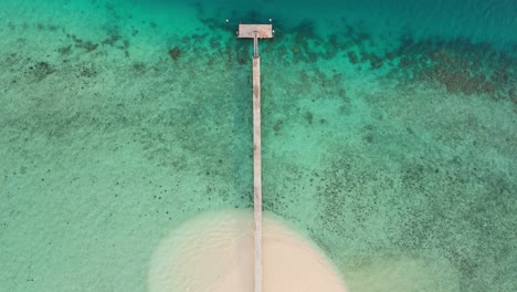 Top-down-drone-shot-of-water-rolling-into-beach-of-private-island-jetty-in-Fiji