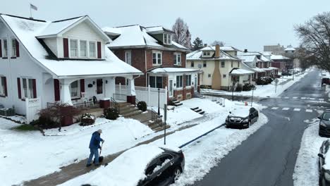 Man-shoveling-sidewalk-after-snow-storm-in-American-neighborhood