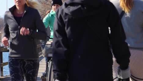 People-ride-bikes-and-kickbikes-and-walk-on-wooden-bridge-in-Stockholm