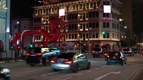 Busy-vehicle-traffic-at-the-intersection-between-New-bridge-road-and-Upper-cross-street-in-Chinatown-with-Yue-Hwa-building-and-Chinese-new-year-dragon-art-installation-in-the-background