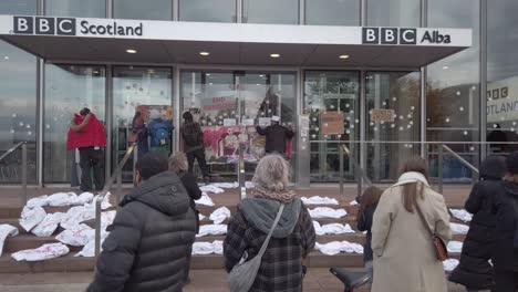 People-putting-up-a-homemade-banner-on-the-front-door-of-the-Scotland-BBC-Headquarters