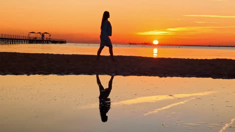 Woman-Walking-Along-the-Beach-with-Morning-Sunrise-in-Silhouette-at-Pickalbatros-Laguna-Vista-Hotel,-Sharm-El-Sheikh,-Egypt