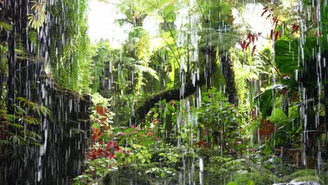 Cinematic-handheld-motion-shot-of-people-walking-on-aerial-walkway-at-cloud-forest,-greenhouse-conservatory-with-waterfall-and-temperature-control,-mist-spraying-to-keep-the-environment-moist