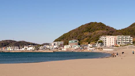 Typical-Japanese-beach-in-seaside-town-with-mountains-during-winter-day-with-few-people