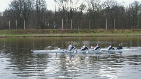 Girls-rowing-on-the-Amsterdam-Bosbaan,-Sideways-drone-follow-shot