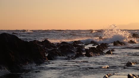 Filmische-Zeitlupenaufnahme-Aus-Niedrigem-Winkel-Von-Silhouettenfelsen-Im-Meer-Bei-Sonnenuntergang