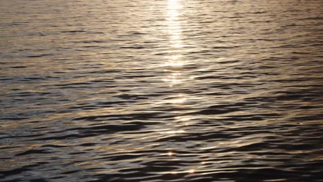 Cerca-Del-Agua-Ondeando-Mientras-La-Cámara-Se-Acerca-Hacia-El-Sol-Y-La-Silueta-De-La-Isla.