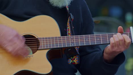 Guitarist-plays-on-wooden-acoustic-guitar,-closeup-view-of-hands,-fingers,-frets-and-strings