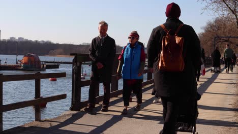 People-of-different-ages-walk-by-water-on-sunny-day-in-Stockholm,-Sweden