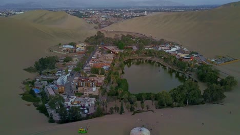Magical-Huacachina-Oasis-Surrounded-by-Desert-Sand-Dunes-in-Peru-from-an-Aerial-Drone-View