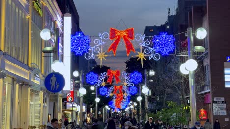 Busy-shopping-street-adorned-with-vibrant-Christmas-lights-at-dusk,-in-Yokohama,-Japan