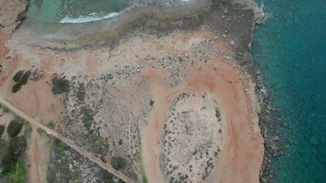 Aerial-top-down-view-of-Ayia-Napa-rocky-pebble-beach-and-turquoise-clear-water-sea-in-Cyprus