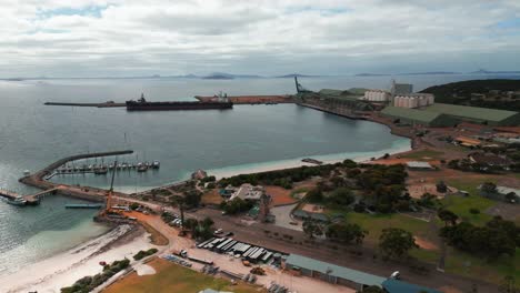 aerial-view-over-Esperance-industrial-harbour-with-a-cargo-ship-beeing-loaded-on-an-overcast-day,-Western-Australia