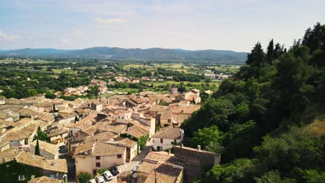 Atemberaubender-Panoramablick-Auf-Hellbraune-Graue-Dächer-Entlang-Bewaldeter-Hügel-In-Cadenet,-Provence,-Frankreich,-Luftaufnahme