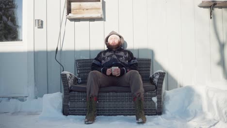 A-Man-is-Seated-on-a-Couch,-Savoring-a-Hot-Drink-During-the-Winter-Season---Static-Shot