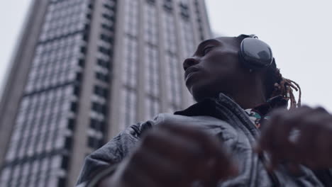 Low-angle-view-on-serious-black-man-with-skyscraper-in-background