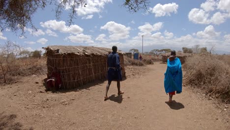 Aldeanos-Masai-Junto-A-Sus-Cabañas,-Familia-Africana-Con-Un-Niño-Recién-Nacido-Con-Túnicas-Habituales