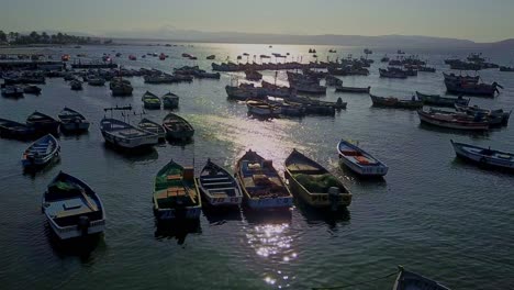 Fishing-Boats-at-El-Chaco-Bay-in-Peru-with-Sunlight-Reflecting-On-the-Water,-Aerial-Drone-Shot