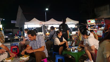 Foreigners-and-locals-eating-on-low-seats-at-typical-night-market-in-Thailand