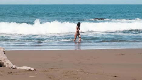 Woman-wading-in-ocean-waves-on-sandy-beach