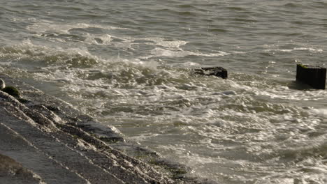 Mid-shot-of-waves-crashing-onto-groynes-and-sea-defences-at-Milford-on-Sea