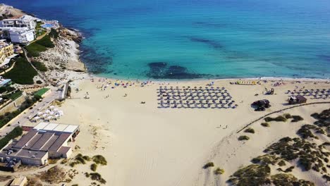 Cala-mesquida-beach-with-crystal-clear-water-and-sunbathers,-bright-summer-day,-aerial-view