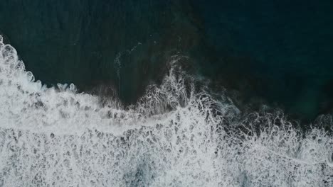 Aerial-view-of-the-ocean-waves-breaking-on-the-beach