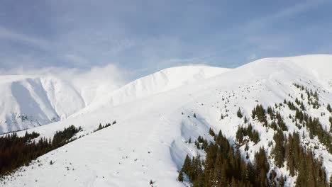 Snow-covered-Papusa-Peak-in-Iezer-Papusa-Mountains,-Arges,-Romania-with-serene-pine-forests