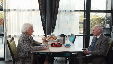 Senior-male-citizen-gets-picked-up-by-caregiver-to-go-for-walk-at-communal-table