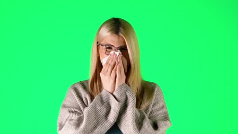 Caucasian-Blonde-Woman-sneezes-and-blows-her-nose-feeling-sick,-young-studio-chroma-green-background-portrait-shot
