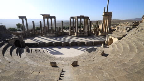 Ancient-Roman-theater-of-Dougga-with-arches-and-steps-under-clear-blue-sky