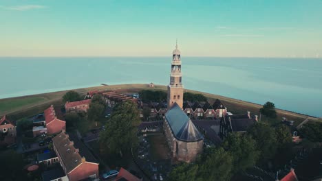 A-historic-church-in-a-coastal-village-at-sunrise,-tranquil-and-picturesque,-aerial-view