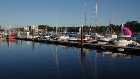 speed-up-shot-of-multiple-sailing-dinghies-sailing-past-moored-up-motor-yachts-and-out-of-frame-on-Lymington-river