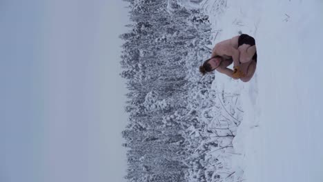 A-Man-is-Taking-a-Break-Before-Attempting-Another-Handstand-in-Deep-Snow---Vertical-Shot