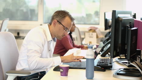 Empleado-De-Oficina-Masculino-Con-Gafas-Escribiendo-Con-Un-Dedo-En-Su-Computadora-Portátil