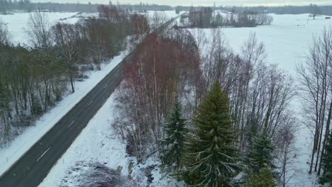 Aerial-drone-shot-of-a-snowy-winter-scene-on-a-rural-empty-highway