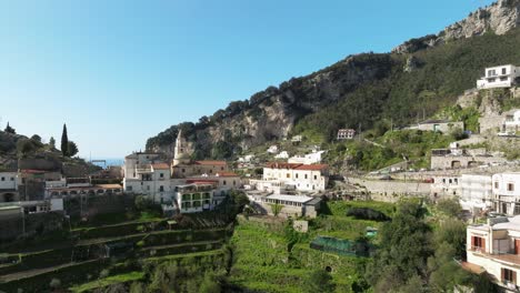 Pueblo-En-La-Ladera-De-Pogerola-Con-Exuberantes-Jardines-En-Amalfi,-Italia,-Bajo-Un-Cielo-Despejado,-Toma-De-Luz-Diurna