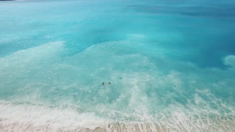 Two-people-swimming-in-the-clear,-turquoise-waters-of-myrtos-beach,-kefalonia-during-daytime,-aerial-view