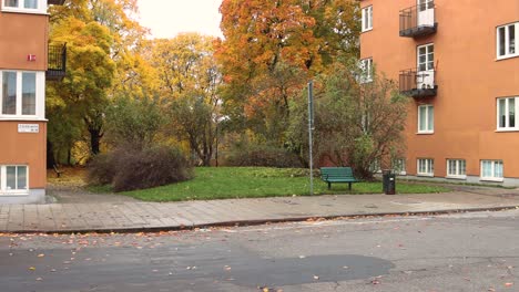 Statische-Aufnahme-Von-Herbstbäumen-Neben-Häusern-In-Stockholm,-Kleiner-Lastwagen-Fährt-Vorbei